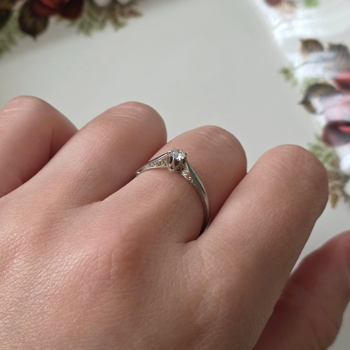 Vintage 18k white gold engagement ring with engravings and a 0.1ct solitaire diamond.