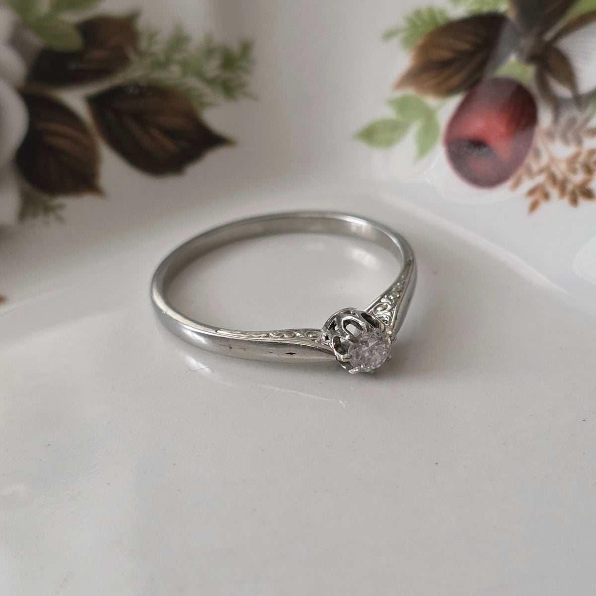 Vintage 18k white gold engagement ring with engravings and a 0.1ct solitaire diamond.