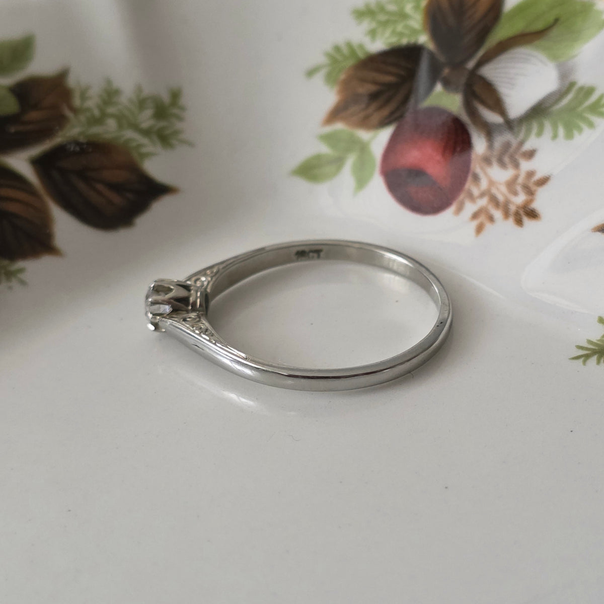 Vintage 18k white gold engagement ring with engravings and a 0.1ct solitaire diamond.