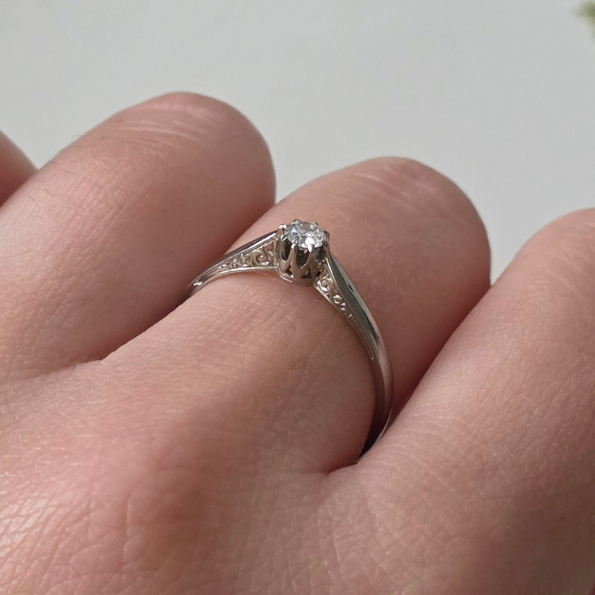 Vintage 18k white gold engagement ring with engravings and a 0.1ct solitaire diamond.