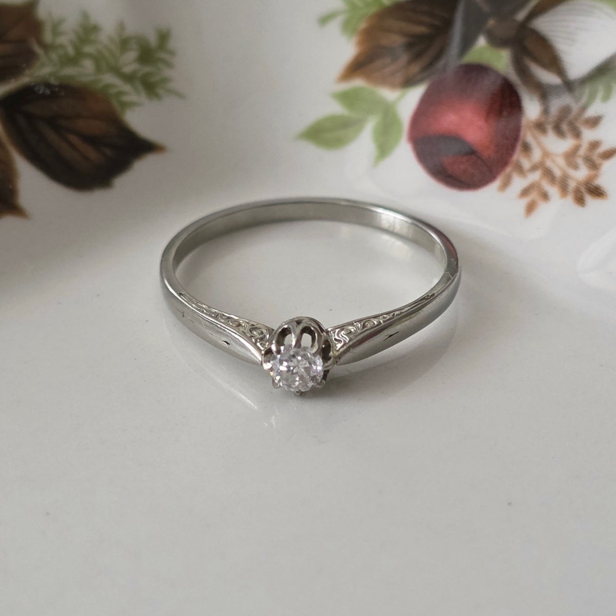 Vintage 18k white gold engagement ring with engravings and a 0.1ct solitaire diamond.