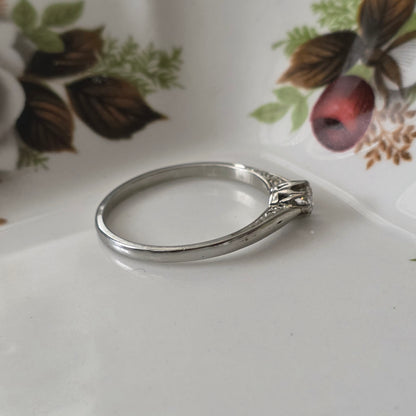 Vintage 18k white gold engagement ring with engravings and a 0.1ct solitaire diamond.