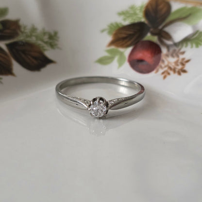 Vintage 18k white gold engagement ring with engravings and a 0.1ct solitaire diamond.